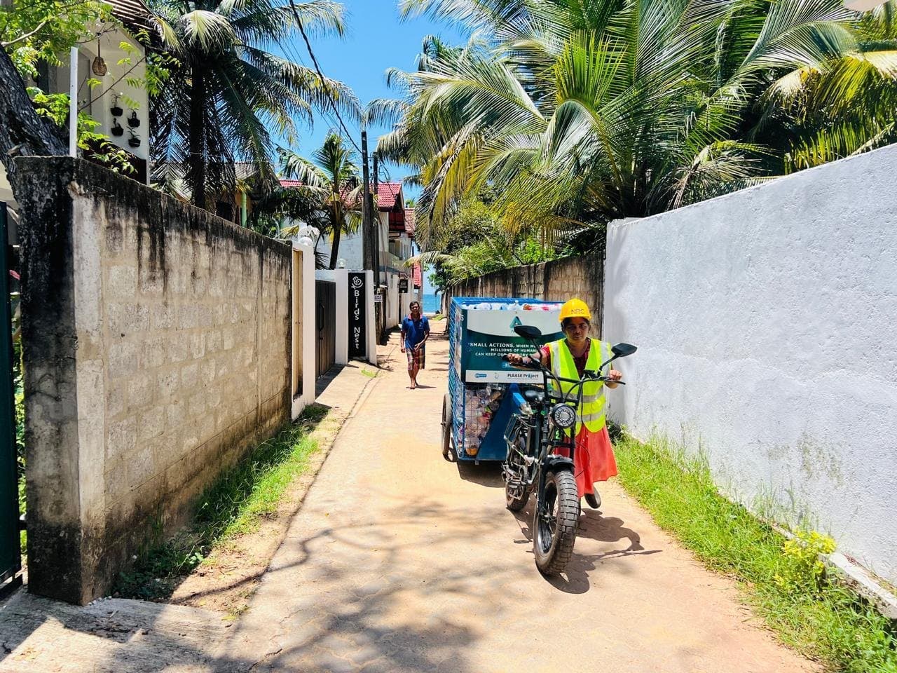 Kanthi wheeling her collection e-bike through a lane in Mirissa.